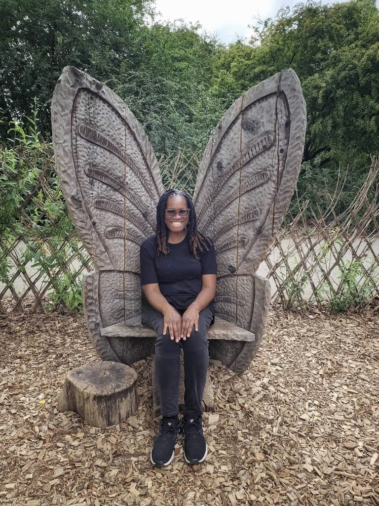 Picture of Allison, owner of the blog, sitting on a wooden butterfly wing bench