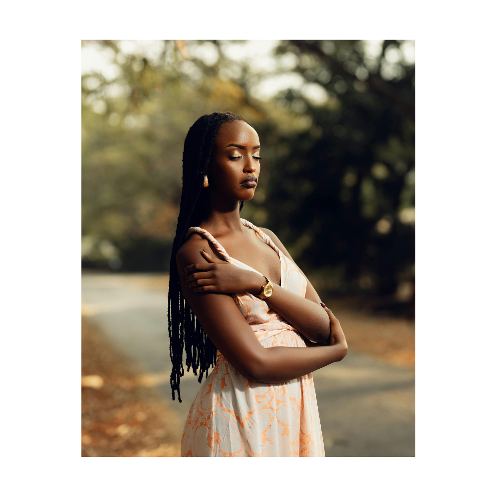 Black woman with braids in a pose of surrender or peace - giving herself a hug while eyes are closed