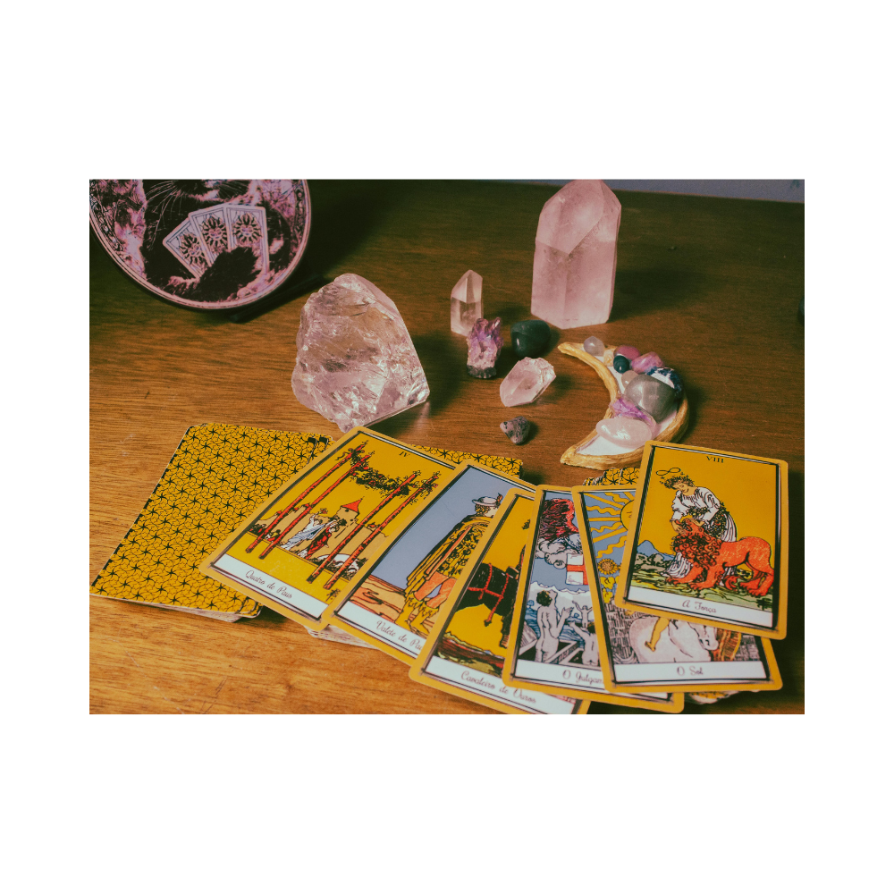 Picture of a Tarot deck with some of the cards facing up on a desk with crystals placed artfully nearby